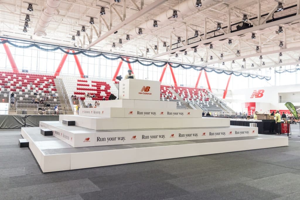 Custom riser pyramid with while fascia and New Balance logos around it, inside the center of The Track at New Balance in Boston, MA