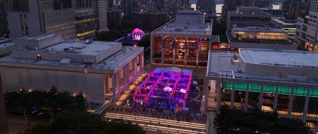 Aerial view from across the street of Lincoln Center looking down on JRPlaza and the dance floor (light up in purpleish-pink), and in the background, you can see the Damrosche Park stage also in the same purpleish-pink.