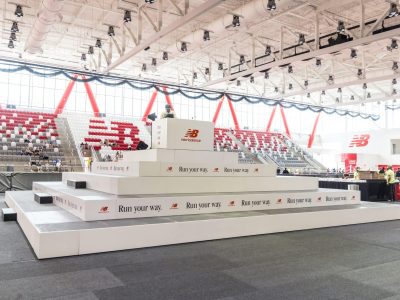 Custom riser pyramid with while fascia and New Balance logos around it, inside the center of The Track at New Balance in Boston, MA