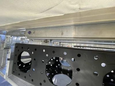 UNikeder rail with mod truss hanging from it under a white roof skin