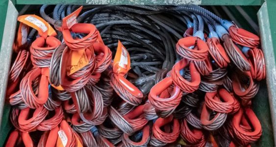 Red steel cables used for entertainment rigging are neatly placed in a box.