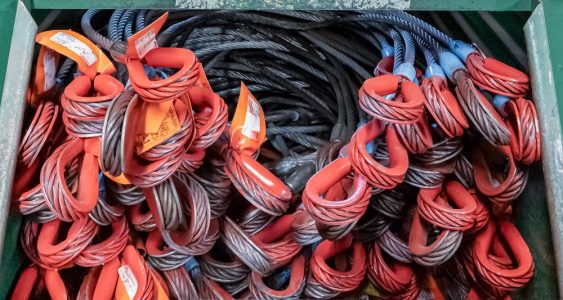 Red steel cables used for entertainment rigging are neatly placed in a box.